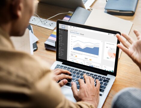 Professionals reviewing business charts on laptop, demonstrating what is low code, image by Novacura