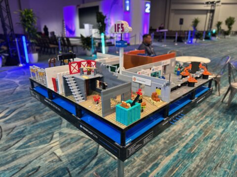 Detailed Lego model layout demonstrating construction, manufacturing, and cloud connectivity labeled Novacura Flow and IFS at a tech event.