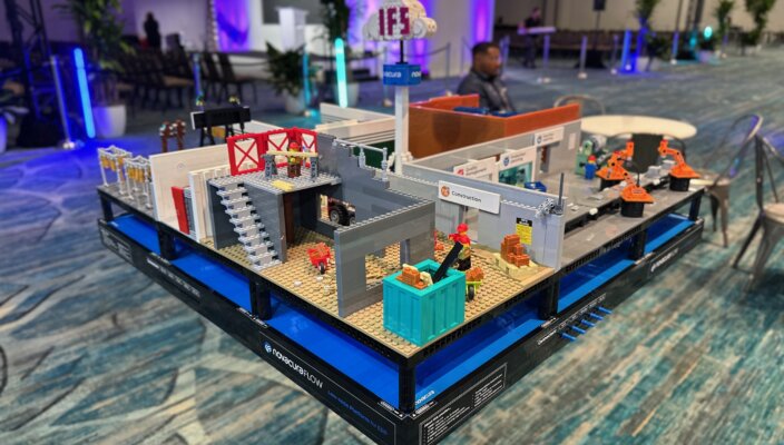 Detailed Lego model layout demonstrating construction, manufacturing, and cloud connectivity labeled Novacura Flow and IFS at a tech event.